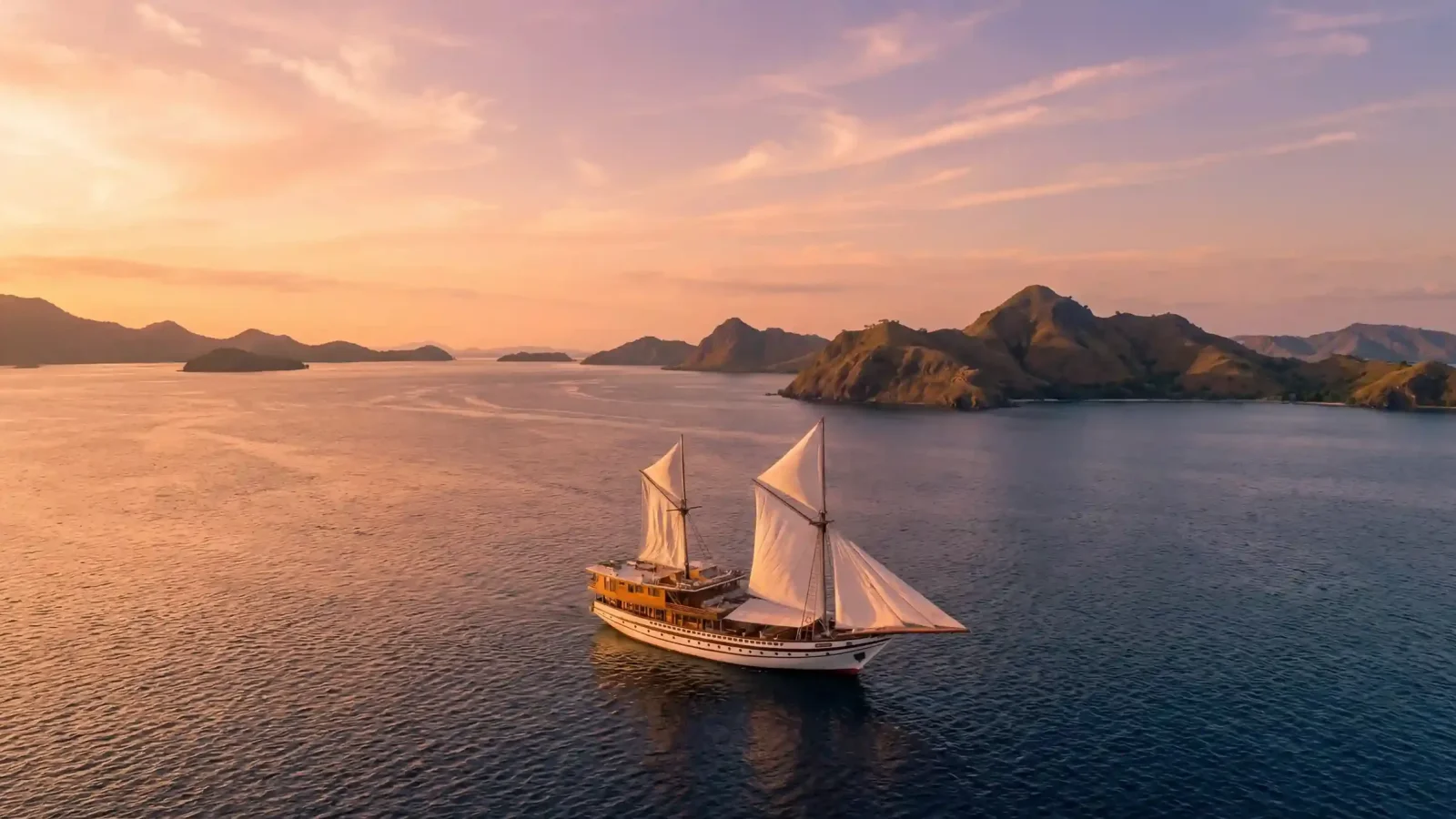 A luxury phinisi sailing past the hills of Komodo Island